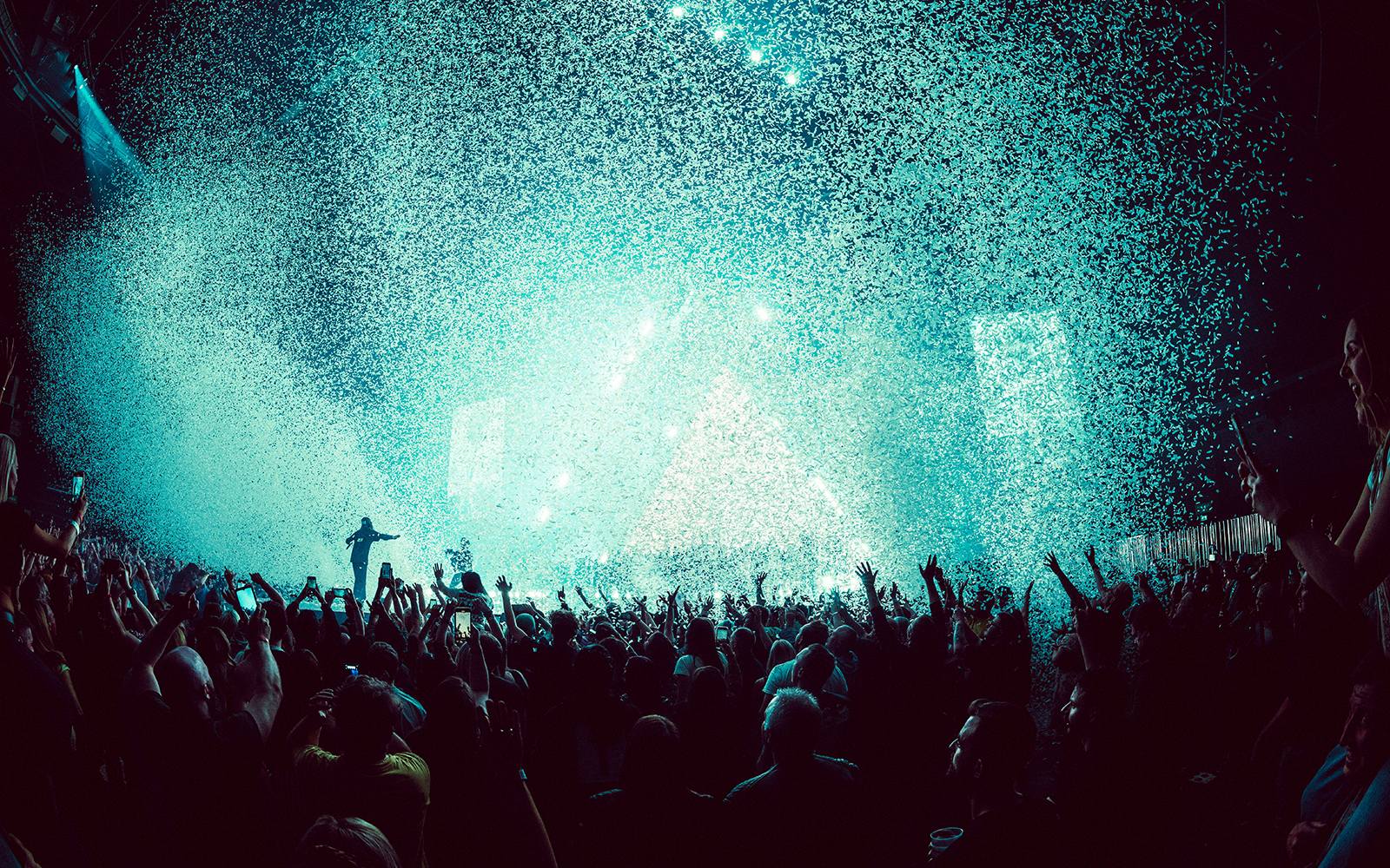 View of stage from the crowd, blue confetti is in the air. 