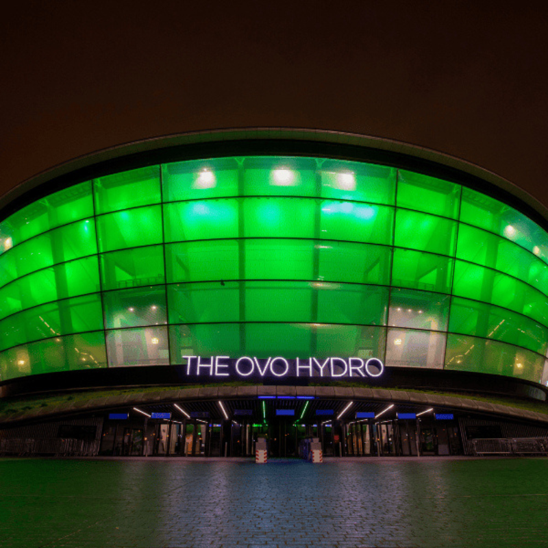 Front view of the OVO Hydro lit up green at night
