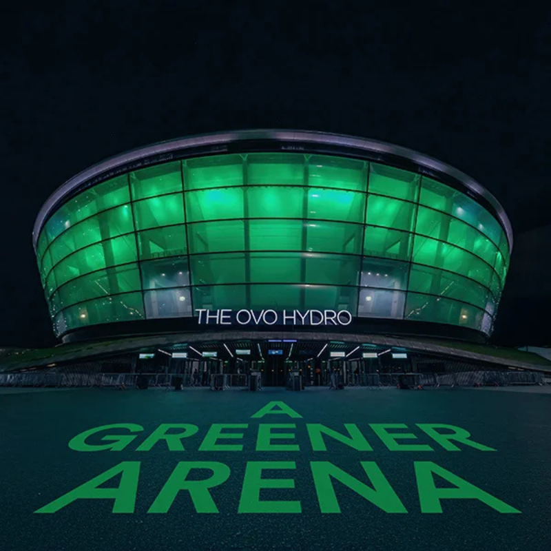 Ovo hydro at night lit up green with "A Greener Arena" on the ground