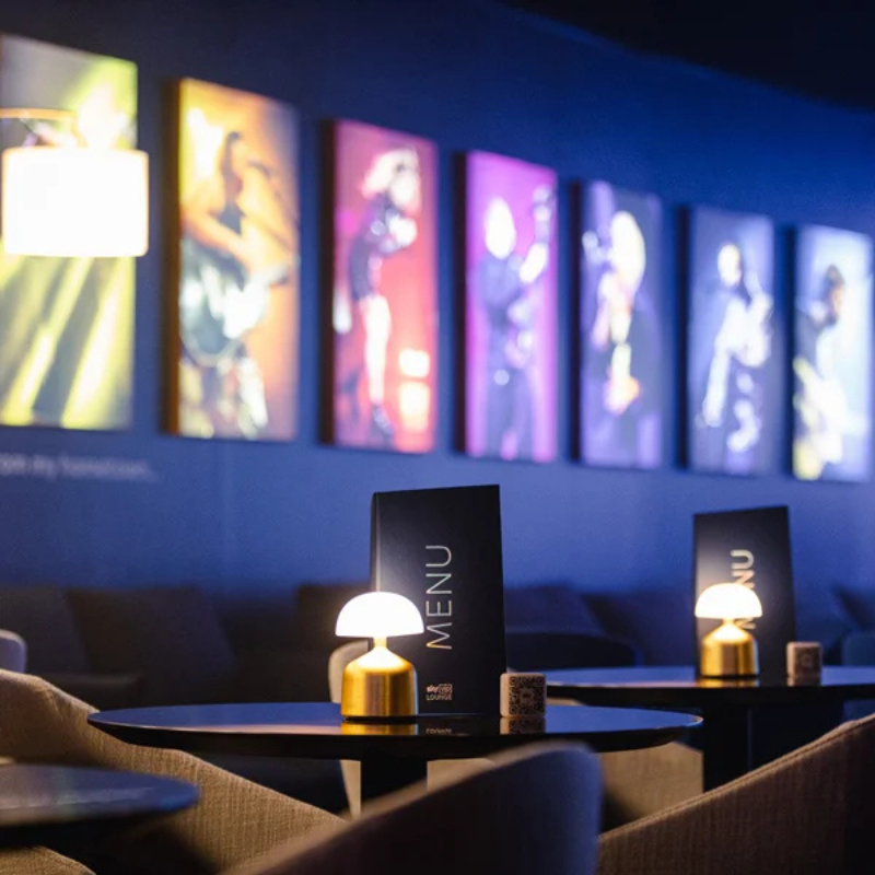 Image of the Sky VIP Lounge with colourful images on the walls and small dimly lit tables