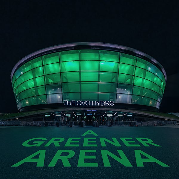 The OVO Hydro at night with the words &quot;A Greener Arena&quot; lit up on the ground in front of the building.