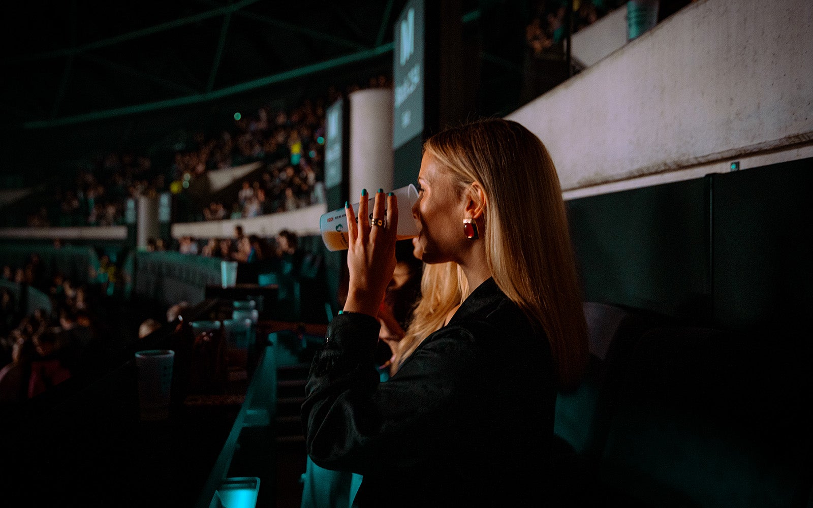 Woman standing drinking beer at a gig at the OVO Hydro.