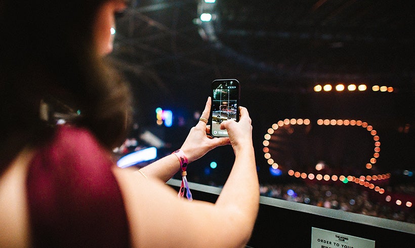 A woman taking a picture of an artist performing.
