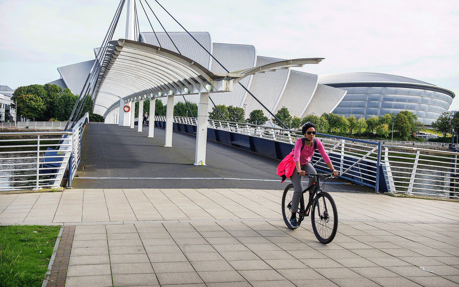Woman in pink cycling across the Bell Bridge with the SEC Armadillo in the background
